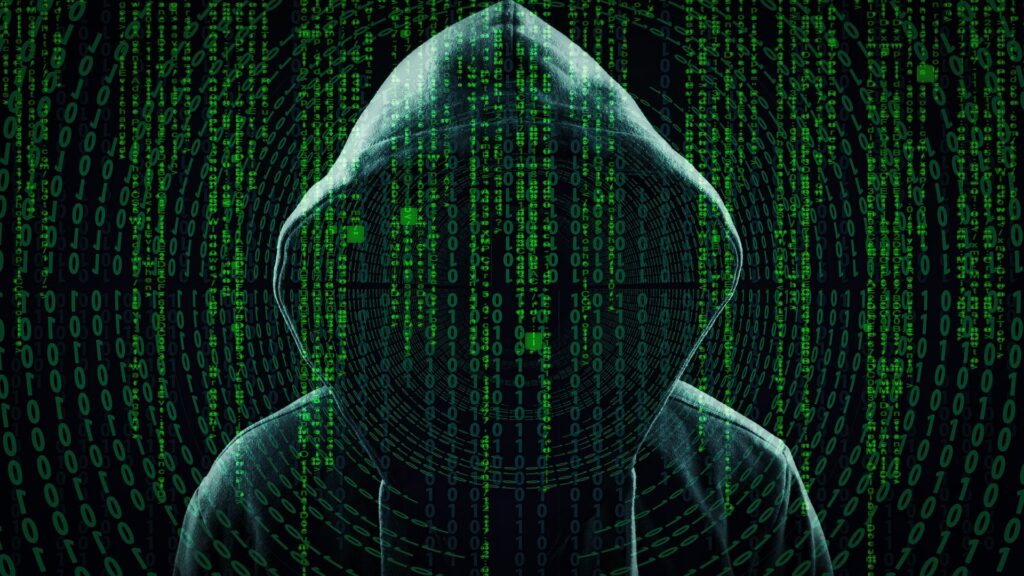 Silhouette de hacker à capuche devant du code binaire vert.